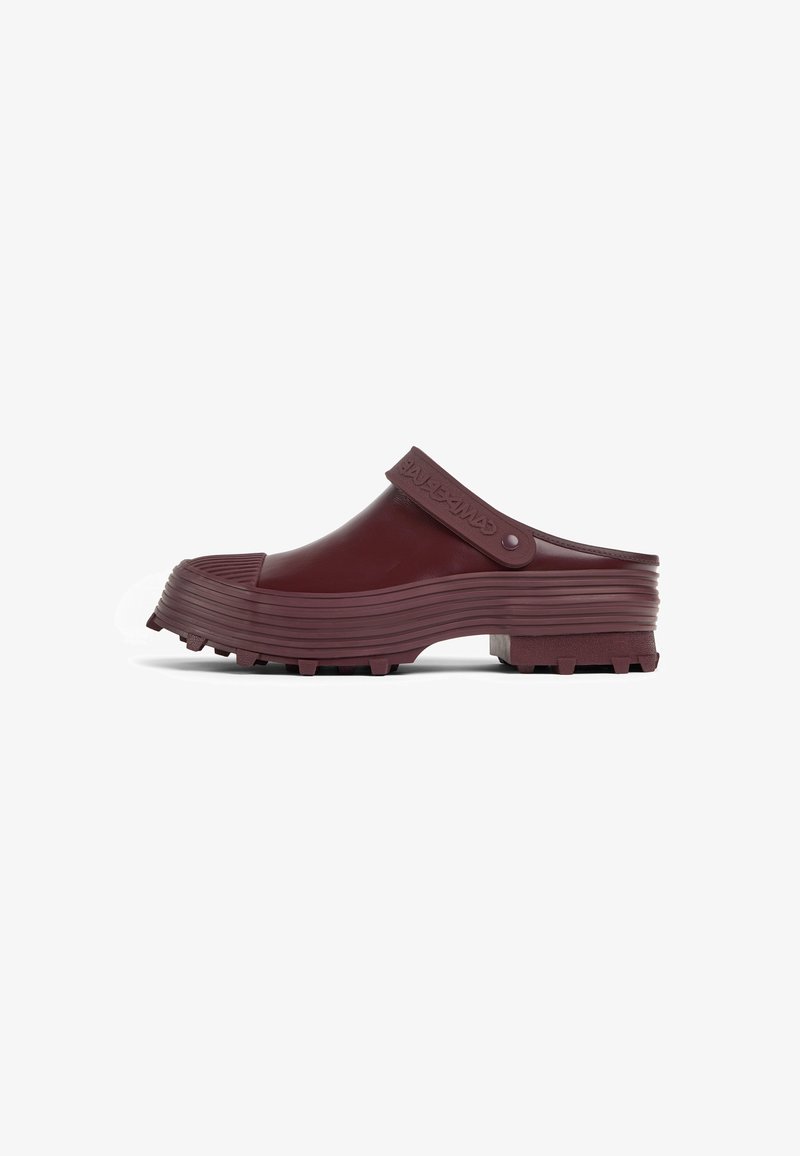 Maroon rubber clogs with ridged texture, chunky treaded sole, and a strap featuring embossed detailing at the ankle.