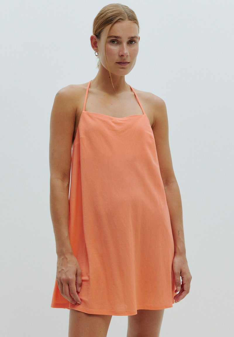 Ein ärmelloses A-Linien-Kleid aus strahlendem Korallestoff, mit dünnen Trägern und einer lässigen Passform. Glatte Textur mit einem einfachen, ununterbrochenen Design.