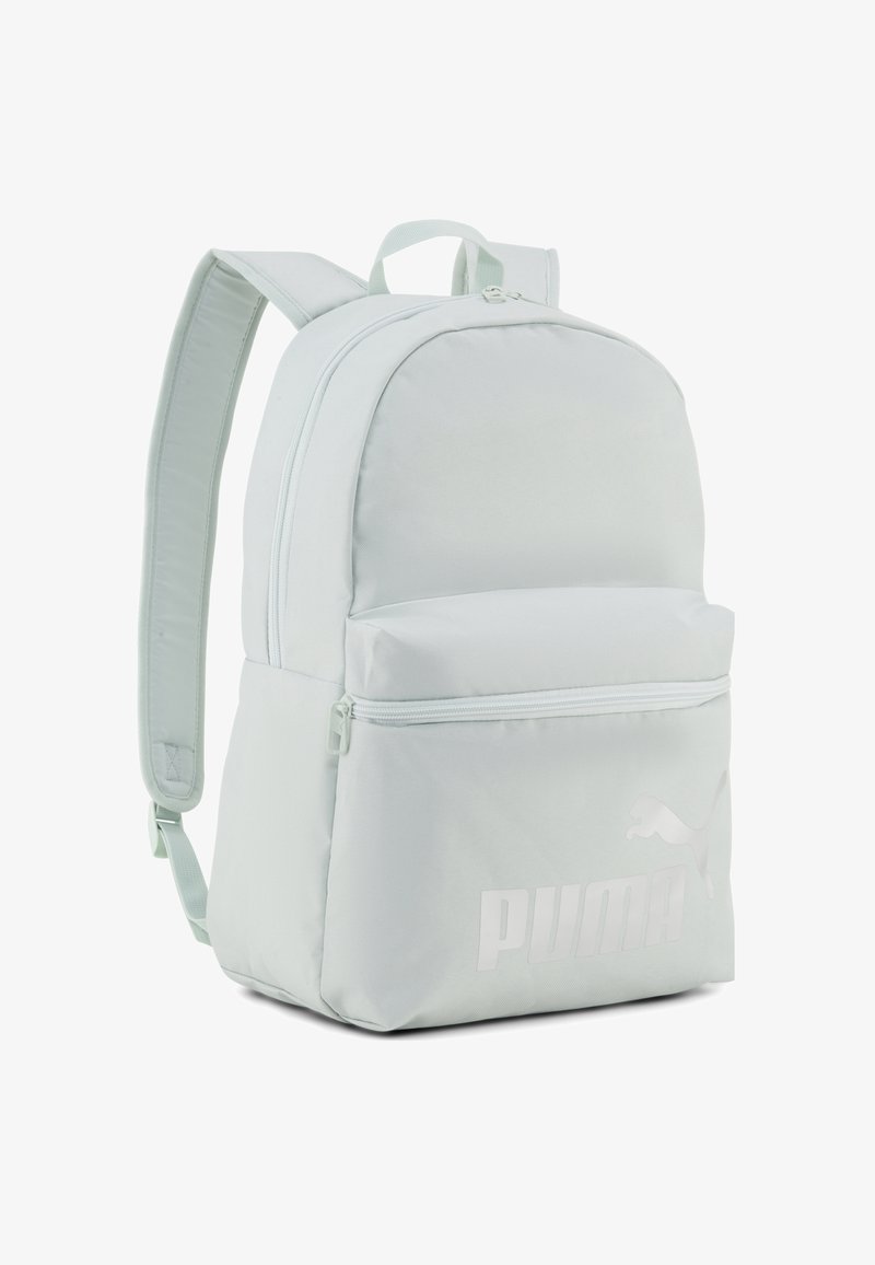 Sac à dos Puma gris clair avec deux bretelles réglables, une poche frontale zippée et un logo Puma discret dans le coin inférieur droit.