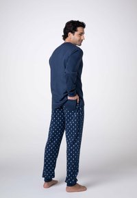 Completo pigiama blu navy composto da una maglietta a maniche lunghe e pantaloni decorati con ippocampi azzurri, realizzato in un tessuto morbido e progettato per il comfort.