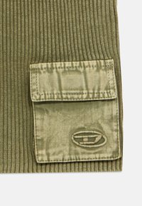 Ύφασμα σε ελιά πράσινο με ανάγλυφη ύφανση, μεγάλο, υφασμάτινο τσέπη και κεντημένο λογότυπο. Διαθέτει λεία επιφάνεια και διακριτικό σχέδιο σε μορφή πλέγματος στην τσέπη.