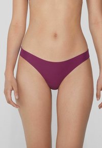 Bikini en tissu bordeaux profond, présentant un design taille basse avec une couverture minimale et une texture lisse, adapté à différents styles.