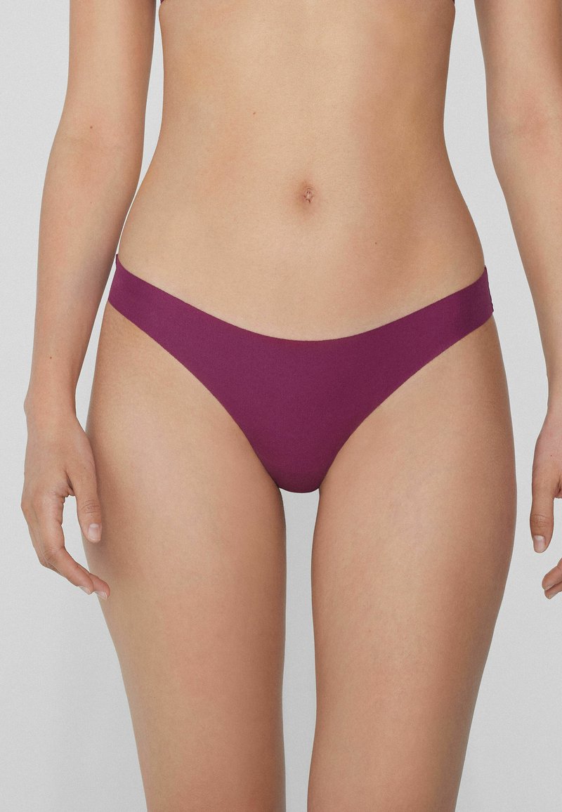 Bikini en tissu bordeaux profond, présentant un design taille basse avec une couverture minimale et une texture lisse, adapté à différents styles.