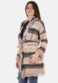 Cardigan a righe beige e nere con bordi frangiati e cinturino, realizzato in materiale morbido, caratterizzato da elaborate bande decorate.