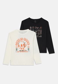 Two long-sleeve shirts, one white with a cartoon skull and text "Life is Good," and one black with skateboards and helmet illustrations.
