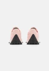 Baskets de sport rose clair avec une tige texturée, une semelle intermédiaire blanche contrastante et une semelle extérieure en caoutchouc noire présentant une forme triangulaire et un motif à pois.