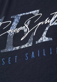 Camiseta de algodón en color navy con texto gráfico en blanco y azul con un efecto texturizado y desgastado, destacando la frase "Deportes de Fútbol."