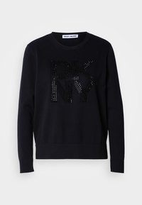 Maglione nero con maniche lunghe e polsini a coste, caratterizzato da un grande logo "DKNY" lucido arricchito da borchie nere sul davanti.