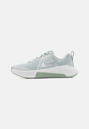 Jasnoszary but do biegania Nike z cholewką z siateczki, białą podeszwą pośrednią, zieloną teksturowaną podeszwą zewnętrzną oraz pętelką na pięcie.