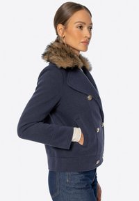 Marineblauer doppelt gefütterter Blazer mit gerippter Textur, Kragen mit Fellbesatz, goldfarbenen Knöpfen und Seitentaschen.