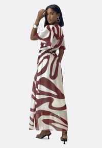 Robe maxi blanche avec de grands motifs abstraits bordeaux, en tissu léger, taille élastique, manches courtes bouffantes et ourlet à la cheville.