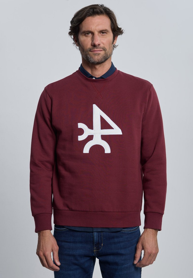 Sudadera granate con cuello redondo, con un gran estampado gráfico blanco en el centro. Hecha de tela suave, tiene puños y dobladillo acanalados.