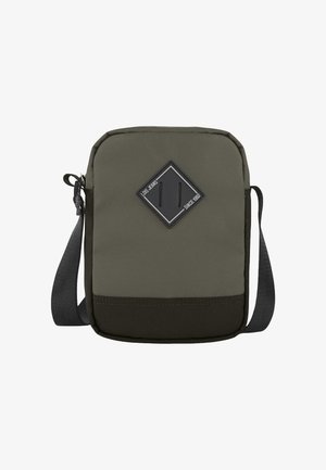 Bolso bandolera cuadrado de tela verde oliva con base negra. Cuenta con un parche con el logo en forma de rombo, correa ajustable y cierre de cremallera.