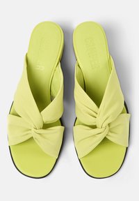 Sandali verde lime con cinturini in tessuto annodati e suole imbottite. Design elegante con suola piatta e dettagli del logo discreti sulla soletta.