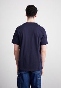 Camiseta de cuello redondo navy, hecha de algodón, de mangas cortas, con textura suave, diseño sencillo, mostrada desde atrás con detalles de costura sutiles.
