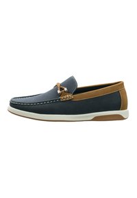 Mocasines para hombre en una parte superior de malla azul marino oscuro, con detalles en cuero marrón y costuras blancas. Cuenta con una suela acolchada y una suela exterior de goma marrón.