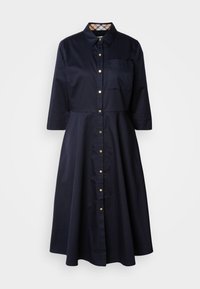 Marineblauwe katoenen shirtjurk met knoopsluiting aan de voorkant, puntige kraag, driekwart mouwen en een borstzak. Kenmerkt zich door een ruitpatroon op de kraag.