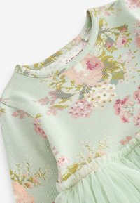 Zelené žebrované šaty s květinovým vzorem v růžové a žluté barvě, s kulatým výstřihem a lehkou tylovou sukní na lemu.