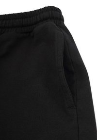 Svarta joggingsbyxor i mjuk bomull med resårmidja och sidoficka, tillverkade av ett slätt, texturerat tyg.