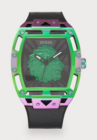 Motif de lion vert sur un cadran noir de montre ; boîtier en métal irisé avec découpes ; bracelet en cuir noir ; aiguilles argentées ; logo affiché en haut.
