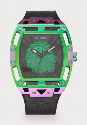 Motif de lion vert sur un cadran noir de montre ; boîtier en métal irisé avec découpes ; bracelet en cuir noir ; aiguilles argentées ; logo affiché en haut.