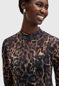 Μακρυμάνικο μπλουζάκι από διάφανη ύλη, με σχέδιο λεοπάρ σε αποχρώσεις καφέ και χρυσού. Υψηλή λαιμόκοψη και κομψή γραμμή.