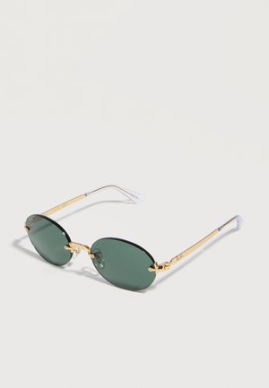 Gafas de sol verdes con forma ovalada, montura de metal dorado y terminales de varilla de plástico transparente, reposando sobre una superficie blanca.