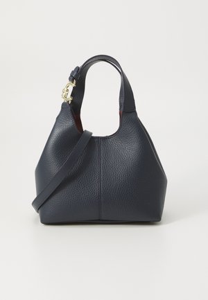 Laukun väri on laivastonsininen, ja siinä on tekstuuripinta, pyöreä yläkahva sekä irrotettava olkahihna. Koristeina on kultaiset yksityiskohdat.