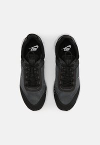 Fekete és szürke sportcipők, hálós felsőrésszel, rács mintázattal és párnázott szegéllyel. Fekete fűzőkkel és fehér Nike logóval a nyelvén.