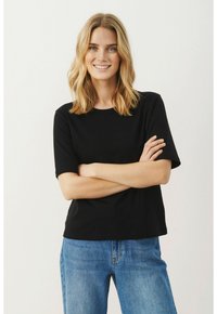 Juodas trumpa rankovė t-shirt, pagamintas iš medvilnės, su apvaliu kaklu ir laisvu kirpimu, derinamas su šviesiai mėlynomis džinsinėmis kelnėmis.