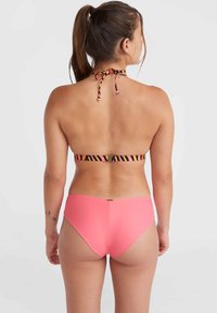 Ensemble de bikini avec un haut à nouer multicolore à rayures et un bas taille haute rose uni. Texture lisse et design ajusté.