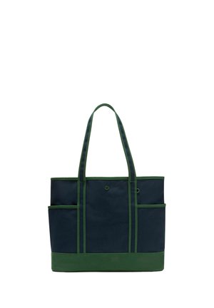 Marineblaue und grüne Tasche mit zwei langen Henkeln, seitlichen Außentaschen und einem kleinen runden Logo auf dem vorderen Mittelpaneel.
