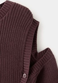 Gilet sans manches en tricot marron foncé avec texture côtelée, encolure ronde et bouton le long de la couture latérale.