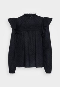 Blusa nera con maniche arricciate, tessuto testurizzato con piccoli motivi a pois e scollatura alta con dettagli arricciati.
