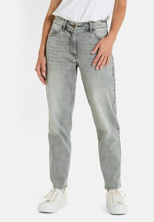 Jean taille haute gris clair avec un design à jambe droite, cinq poches et une fermeture à bouton métallique, associés à des sneakers blanches.