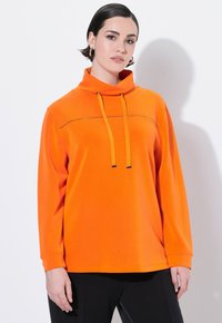 Maglione arancione brillante con colletto alto, coulisse e un dettaglio di cucitura orizzontale sul petto. Maniche lunghe e texture morbida.