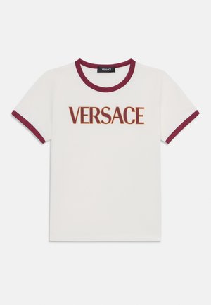Balta trumpa rankovėmis marškinėliai su bordo spalvos apykakle ir rankovių kraštais. Priekyje matomas ryškus "VERSACE" logotipas rudos spalvos. Medžiaga - medvilnė.