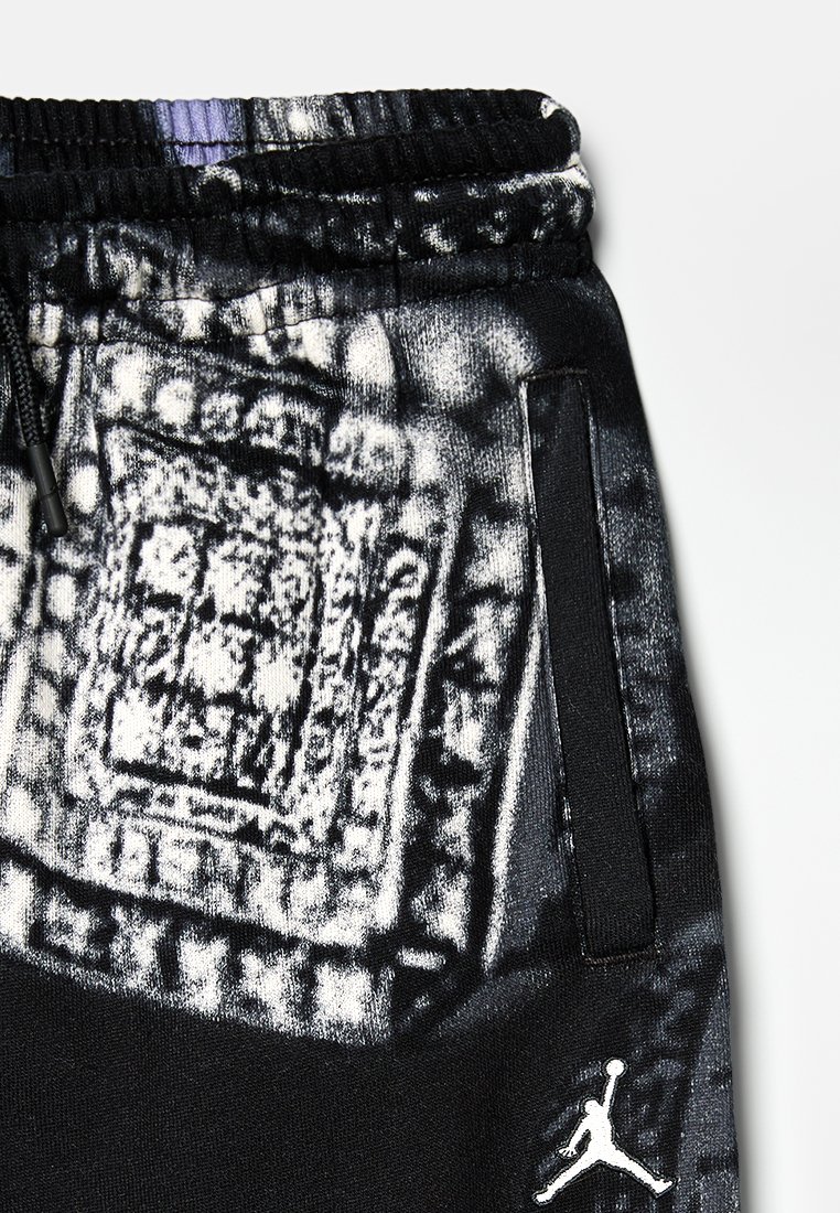 Schwarze Jogginghosen mit einem strukturierten, abstrakten grauen Muster, elastischem Bund und Seitentaschen. Enthält einen weißen Logo-Akzent.