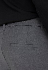Grau Stoffhosen mit strukturiertem Finish, ausgestattet mit einer einzelnen Gesäßtasche und einem elastischen Bund für zusätzlichen Komfort.