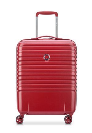 Red hard-shell suitcase with vertical grooves, retractable handle, and four spinner wheels. Features a metallic logo and zipper closure.