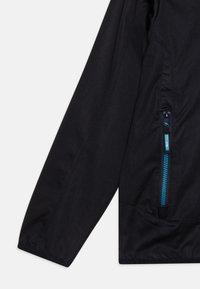 Black outdoor jacket with a zippered pocket, featuring contrasting blue zipper, smooth texture, and tailored fit for weather resistance.