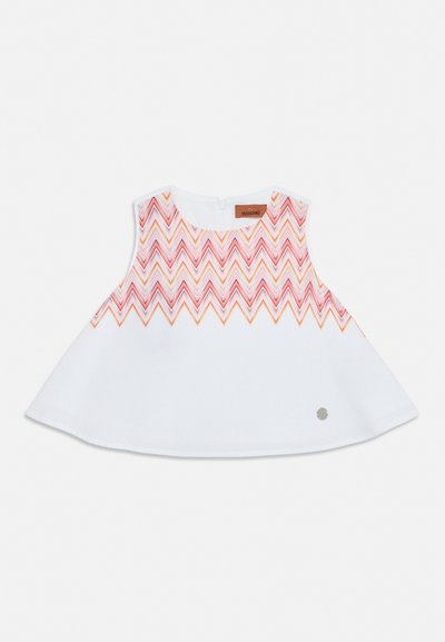 Robe bébé blanche sans manches avec motif zigzag rose et orange sur le haut et étiquette de marque près de l’encolure, bas évasé.