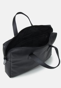 Sac fourre-tout en cuir noir avec une surface texturée, fermeture éclair, deux poignées et un intérieur spacieux noir. Comprend des poches intérieures pour l'organisation.