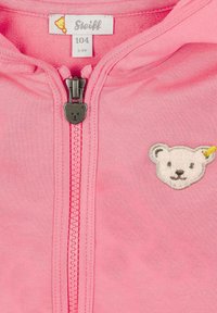 Rosa Kapuzenjacke mit Reißverschluss aus weichem Stoff, ausgestattet mit einem reißverschlussförmigen Bärenanhänger und einem gestickten Bärenkopf auf der Brust. Größenetikett: 3-4 Jahre.