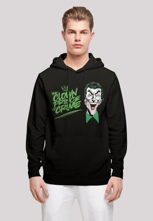 Svart hettegenser med grafikk av en smilende karakter med grønne detaljer, tekst som leser "The Clown Prince of Crime", og en frontlomme.