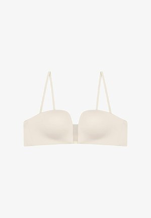 Cream strapless bra with smooth fabric, molded cups, and flat seams. Features narrow adjustable straps and a hook closure at the back.