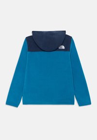 Niebieska polarowa kurtka z granatowym kapturem i ramionami, z logo The North Face na górnej prawej części pleców.