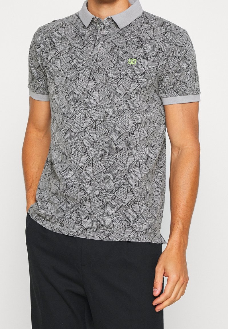 Polo gris avec un motif de feuilles texturé, présentant un col gris clair et des manches courtes, arborant un petit logo vert.