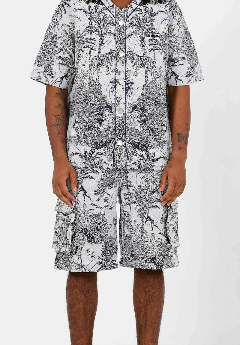 Set di camicia a maniche corte e pantaloni corti, con un motivo floreale in bianco e nero. Davanti con bottoni e vestibilità rilassata, realizzato in tessuto leggero.