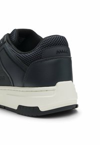 Dark navy sneaker with a textured mesh upper, leather accents, a white midsole, and a patterned rubber outsole. Features subtle branding.
